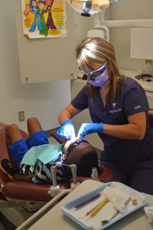 Dental hygienist cleaning a child's teeth at Healthy Smiles clinic.